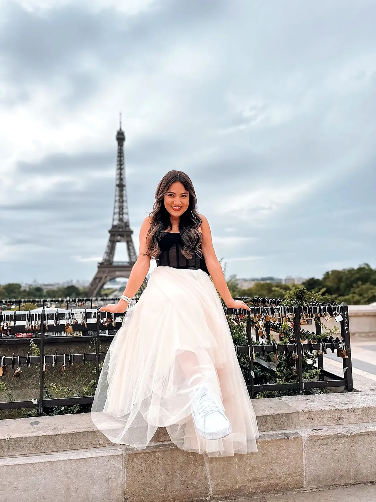 Camila de boina vermelha comendo um croissant numa mesa de café, em Paris