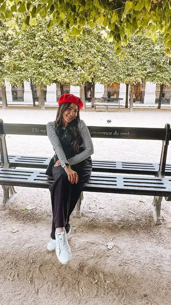 Página do guia: Camila sentada num banco de jardim em Paris