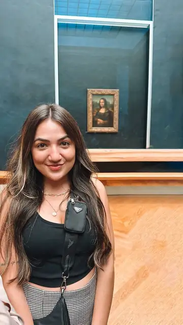 Camila sorrindo diante da Mona Lisa, no Louvre