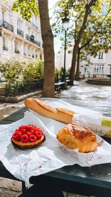 Tortinha de framboesa e croissant sobre papel, numa mesa